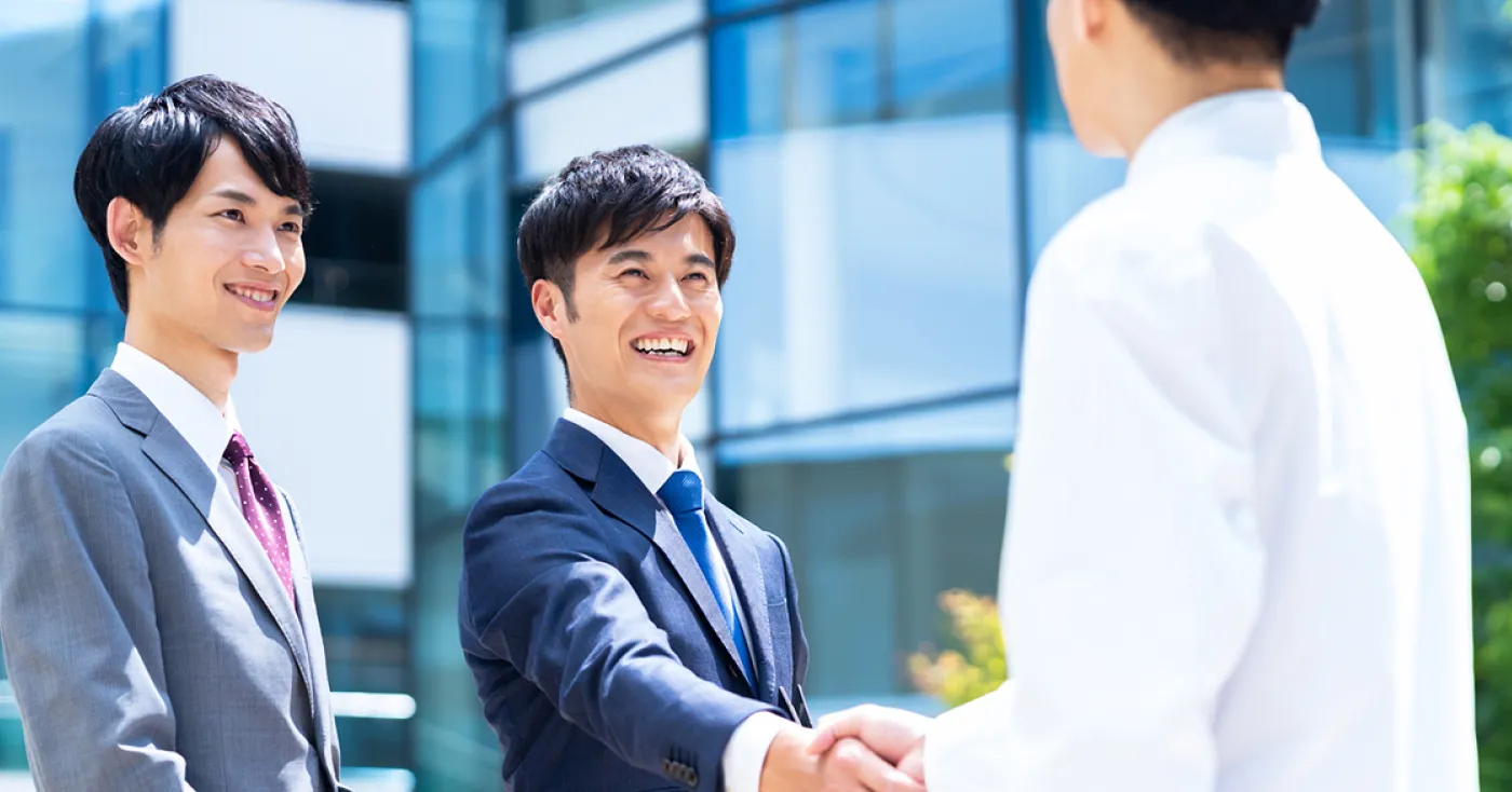 医療現場で握手を交わす男性2名の写真